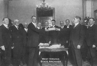 West Virginia State Treasurer W. S. Johnson presenting a
check
to Virginia Attorney General Judge Rhea for debt settlement
